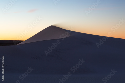 Golden colours of sunrise behind sand dunes