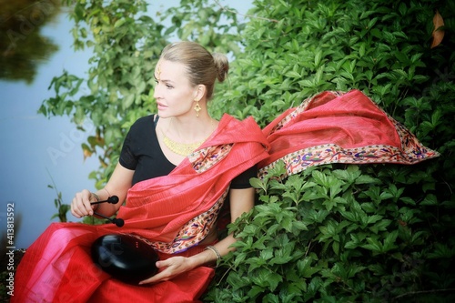 a girl in a national Indian outfit with a musical instrument ufo drum