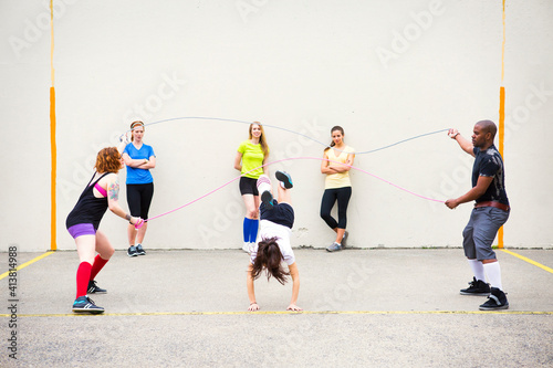 Women looking at friends performing double Dutch on street photo