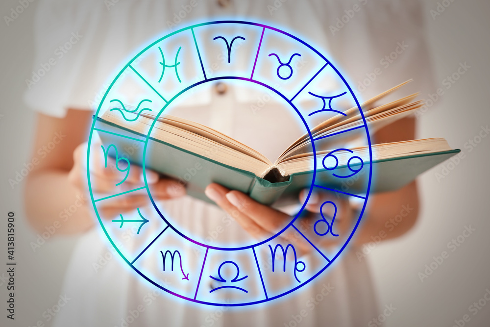 Young woman reading book and illustration of zodiac wheel with astrological signs on light background