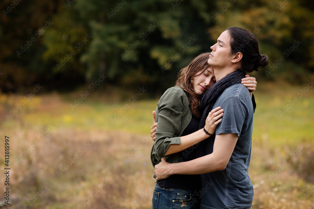 Couple embracing while standing on grassy field Couple embracing while standing on grassy field