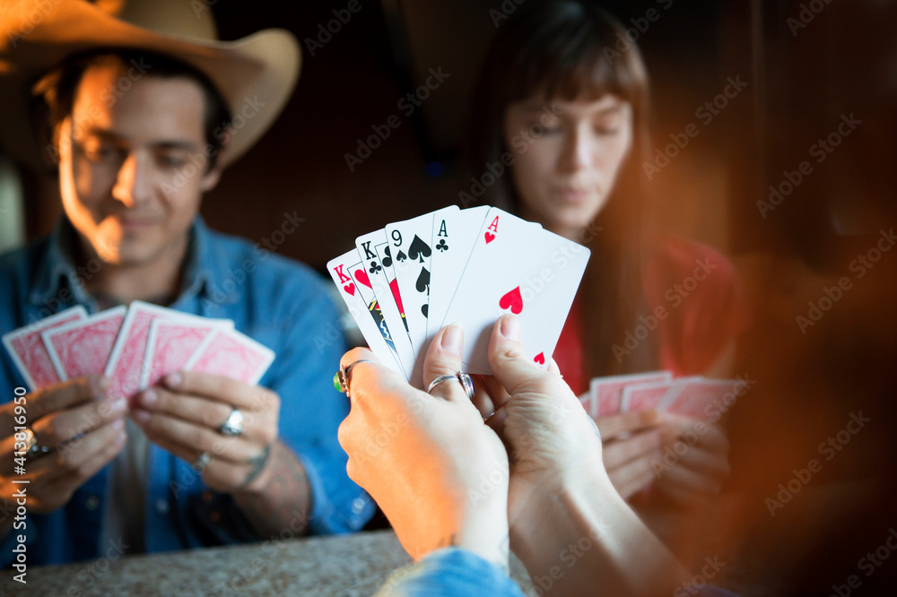 Cropped image of woman holding cards while playing with friends in camper van Cropped image of woman holding cards while playing with friends in camper van
