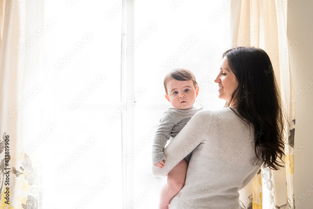 Portrait of cute son carried by mother against window at home Portrait of cute son carried by mother against window at home