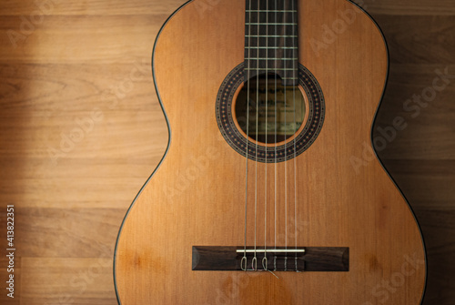 Acoustic guitar resting against a wooden background