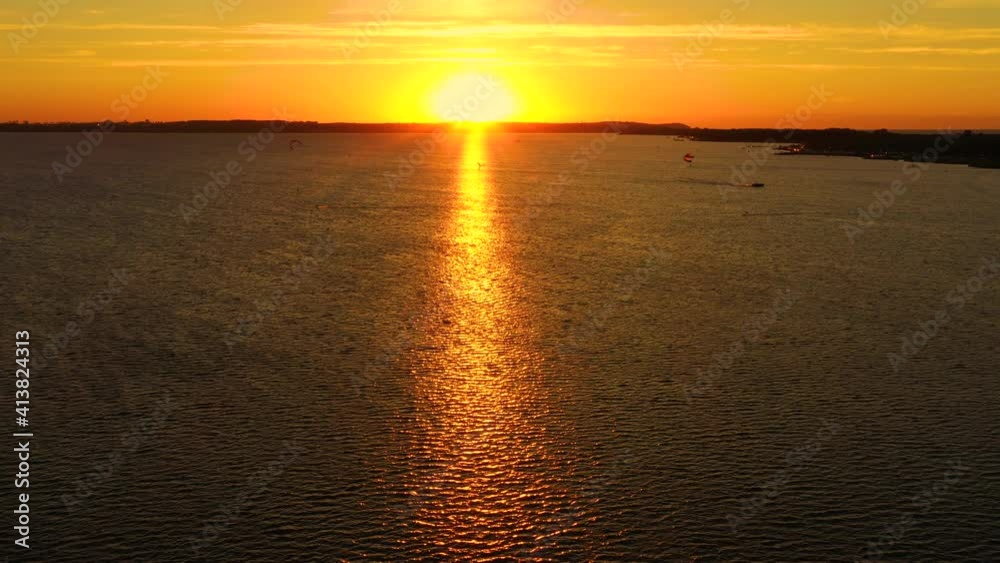 Aerial view, Kitesurfers swim at high speed in the open sea at sunset. Drone shot at three athletes on boards floating above the water surface. Poland Hel