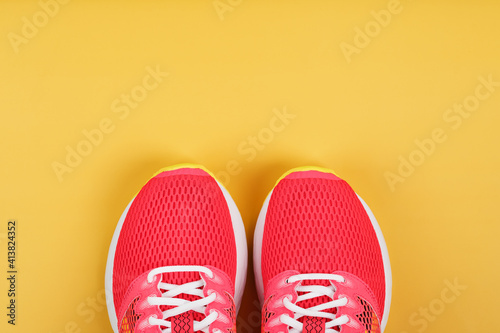 Sports sneakers, pink on a yellow background with free space.