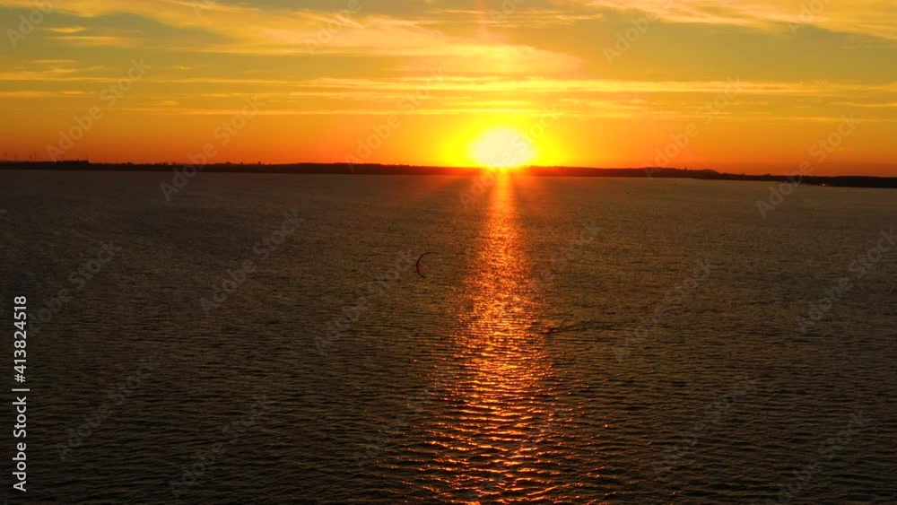 Aerial view, Kitesurfers swim at high speed in the open sea at sunset. Drone shot at three athletes on boards floating above the water surface. Poland Hel