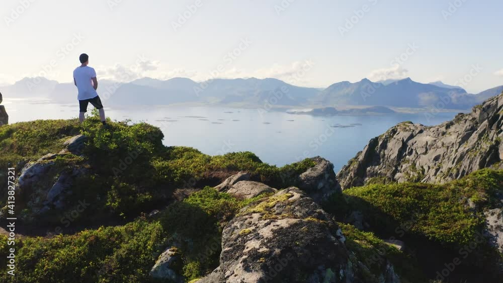 Flying around a hiker on top of mount Festvagtind on Lofoten Islands, Norway