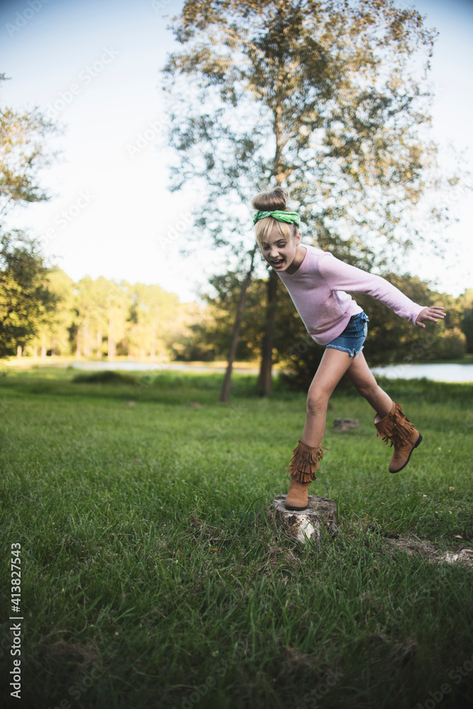 Playful girl screaming while jumping on tree stump against sky in park Playful girl screaming while jumping on tree stump against sky in park