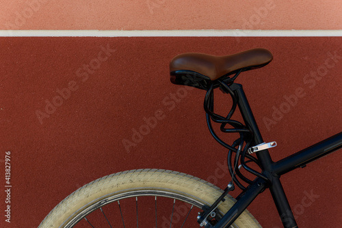 Cropped image of bicycle parked by brown wall in city photo