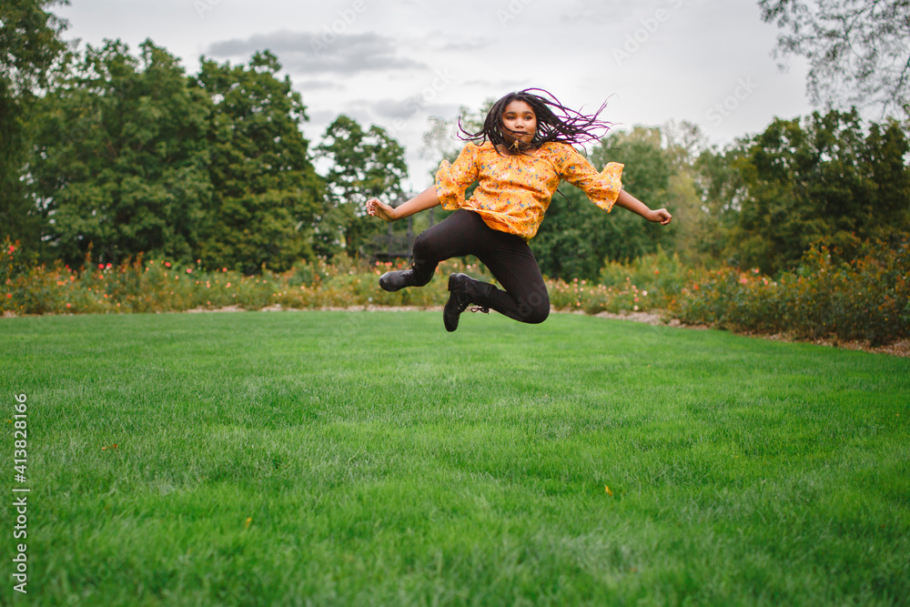 Happy girl jumping on grassy field against sky at park Happy girl jumping on grassy field against sky at park
