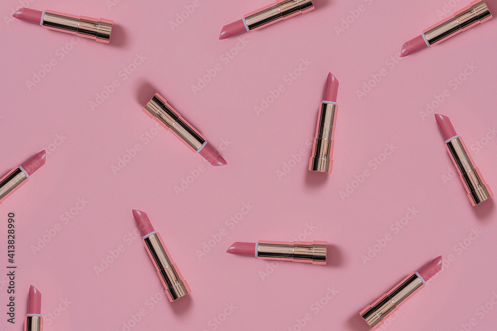 Pink lipstick in golden tube on light pastel pink background. Decorative cosmetic background. Pink lipstick in golden tube on light pastel pink background. Decorative cosmetic background.
