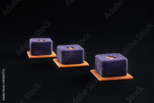 Fototapeta Naklejka Na Ścianę i Meble -  Violet crunchy cakes with cream isolated on black.