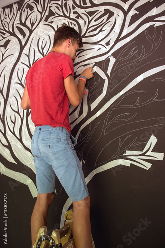 The young man who cuts the branches of a custom tree on the wall photo