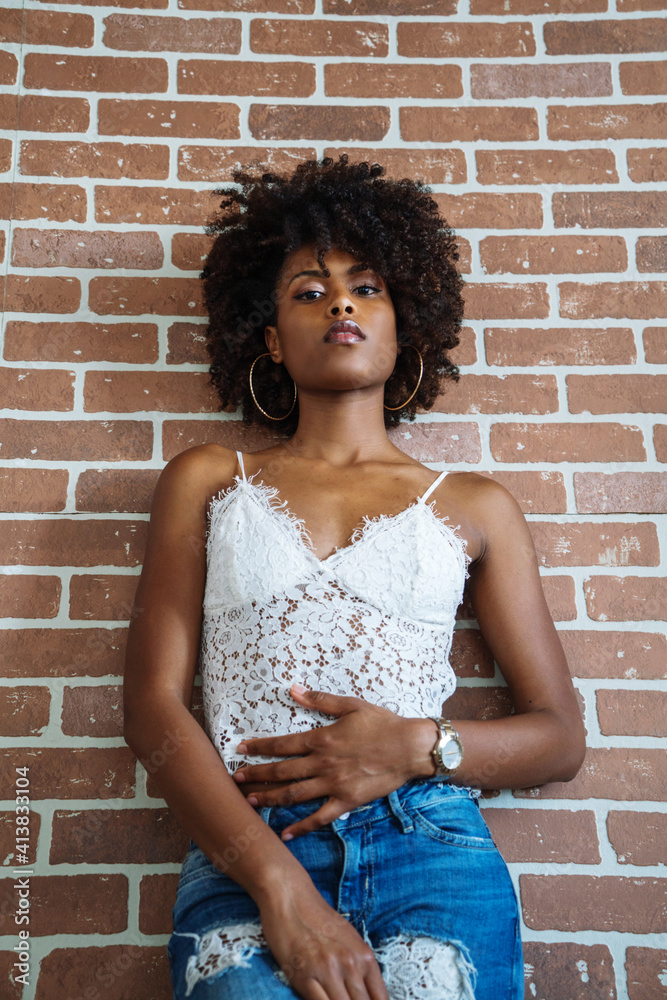 Portrait of a beautiful black woman with afro against the brick wall background