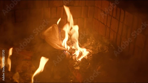 Close up footage of a small fire inside of a burn pit burning trash.