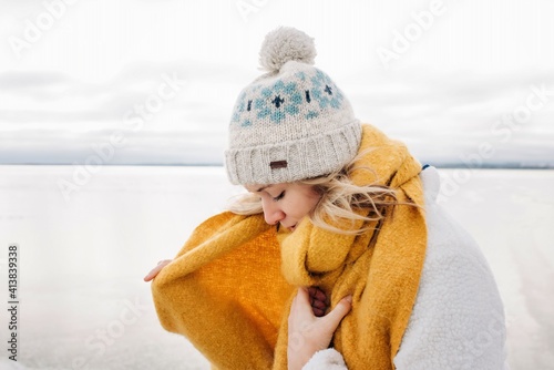 portrait of blonde woman wrapping up warm at the beach in winter photo