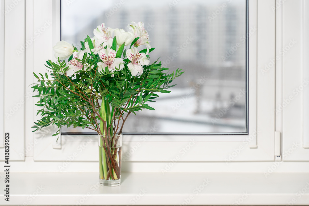 bouquet of decorative white lilies in a vase on the window