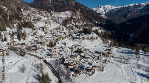 Aerial drone view of valley around Cortina d'Ampezzo, looking from the village of Volo di Cadore towards the snowy hills in february on a sunny day.