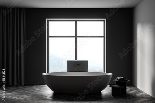 Wooden grey bathroom with bathtub and towels near window