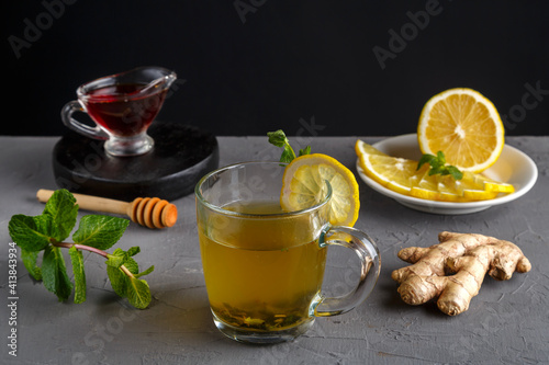 immune ginger drink with honey mint and lemon in a glass cup next to ingredients.