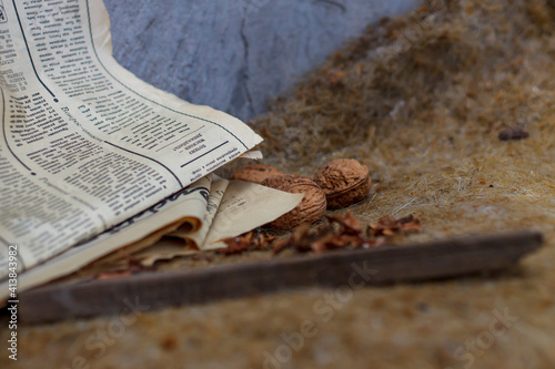 Walnuts lie on dry grass with an old newspaper in cloudy weather side view