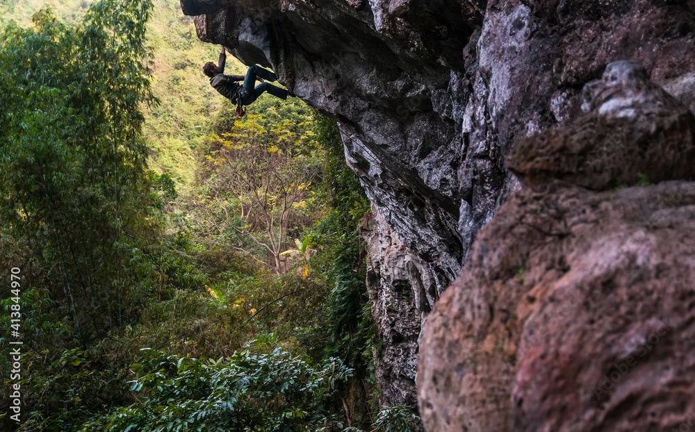 Man rock climbing overhanging cliff in Hidden Valley, Vietnam Man rock climbing overhanging cliff in Hidden Valley, Vietnam