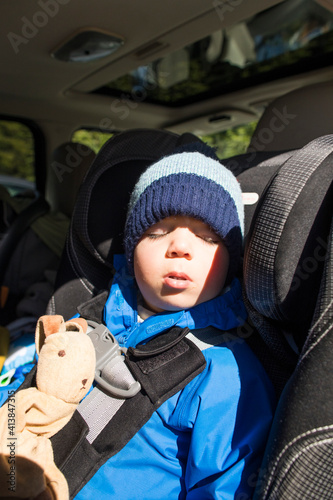 Toddler boy sleeping in his car seat during a road trip. photo