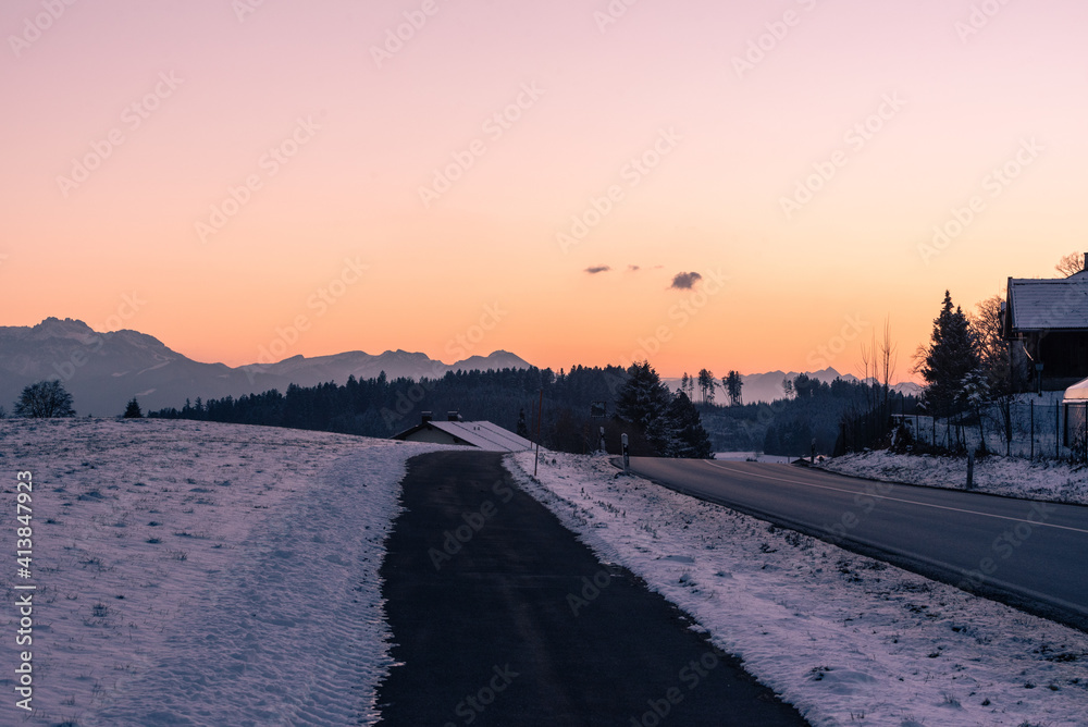 Sonnenuntergang bei Sondermoning in den Ostalpen im , Chiemgau mit Bergen, Schnee, und Wiese