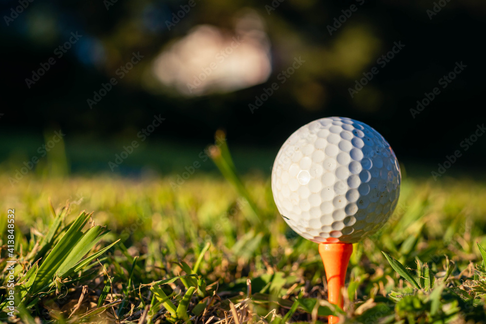 tee stand on grass hole tee and golf ball at sunset tee stand on grass hole tee and golf ball at sunset