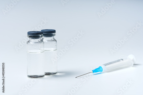 Close up glass vial with flu vaccine and syringe with needle. The concept of vaccination or preventive treatment of injection diseases.