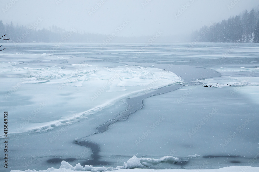 view of frozen lake in mountains during a snow storm view of frozen lake in mountains during a snow storm