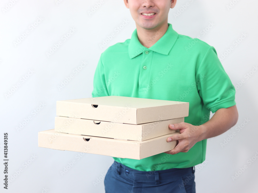 Smiling young Asian delivery man in green T-shirt uniform holding pizza boxes on white background, tracking, shipping and courier delivery services express concept. Smiling young Asian delivery man in green T-shirt uniform holding pizza boxes on white background, tracking, shipping and courier delivery services express concept.