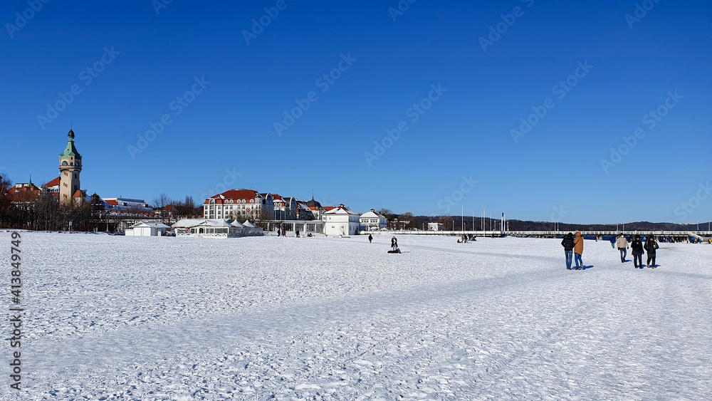 People are walking on a snow-covered beach in Sopot on a beautiful sunny day, Poland