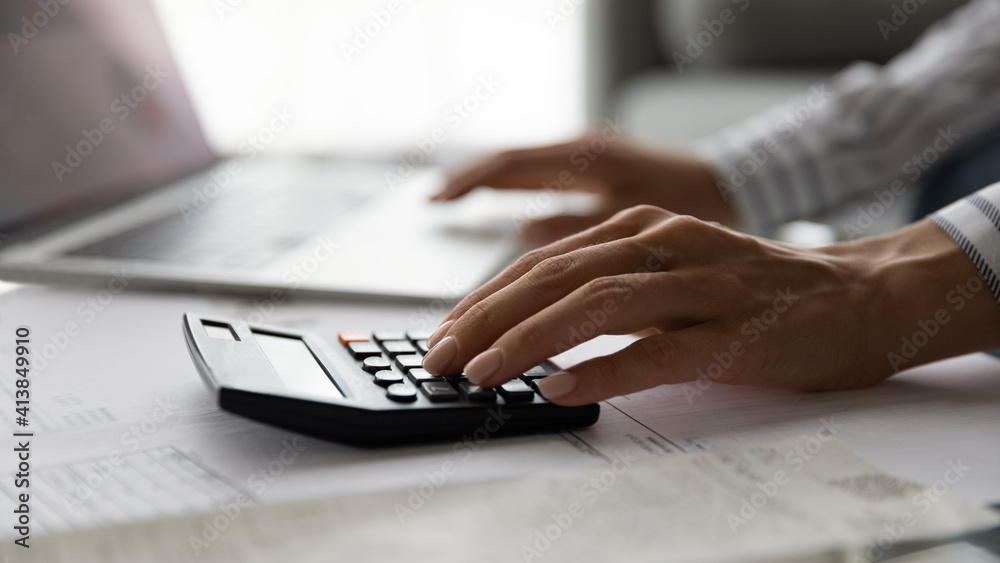 Close up cropped view of young woman accountant auditor doing paperwork at desk full of financial documents control accounting entries check transaction. Focus on female hand pressing calculator keys Close up cropped view of young woman accountant auditor doing paperwork at desk full of financial documents control accounting entries check transaction. Focus on female hand pressing calculator keys