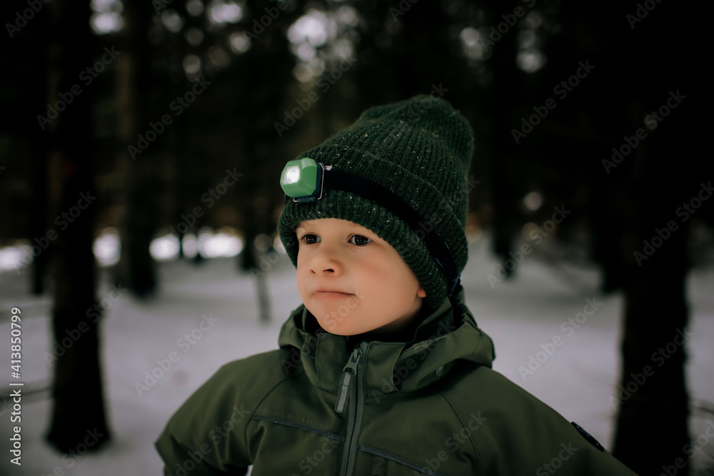 Young boy aged 6 standing outside in the snow with head torch camping