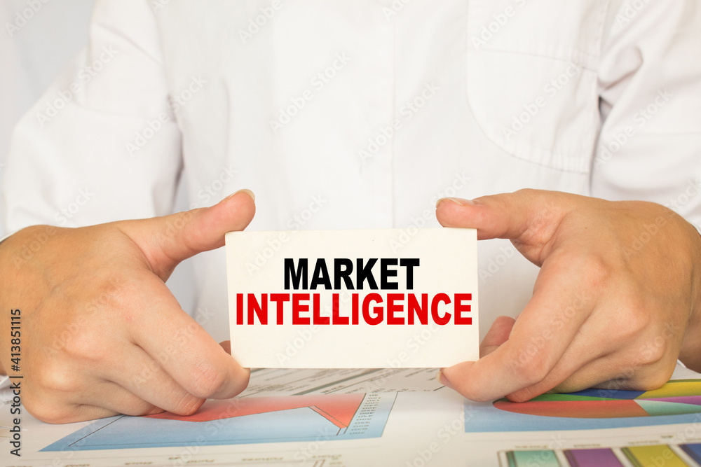 a man in the office holds a card with text MARKET INTELLIGENCE . business concept a man in the office holds a card with text MARKET INTELLIGENCE . business concept