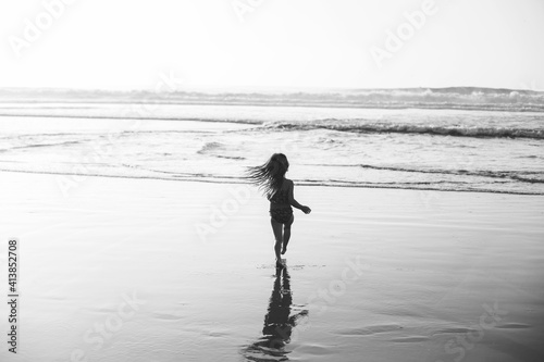 Carefree and independent child adventurously runs into crashing waves. photo