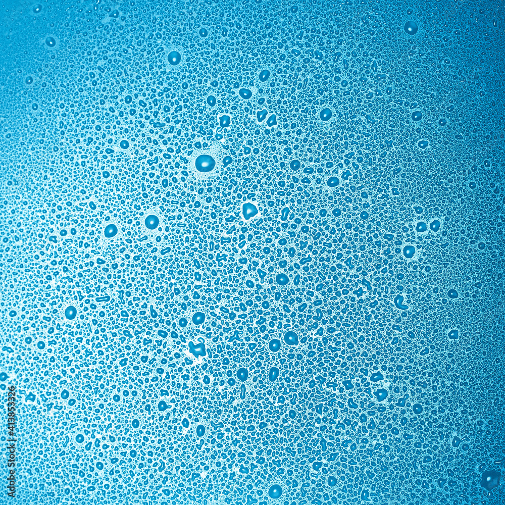 Water droplets of different sizes on a flat, smooth surface.