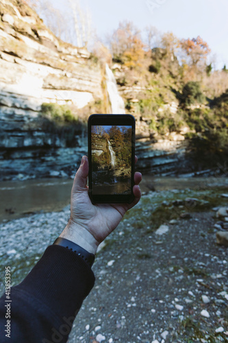 Point of view while taking a photo with smart phone to waterfall photo