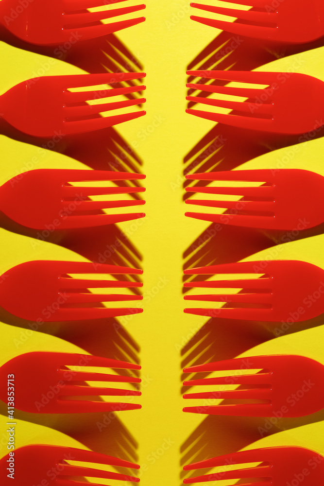 Red disposable plastic cutlery on a yellow table. Red disposable plastic cutlery on a yellow table.