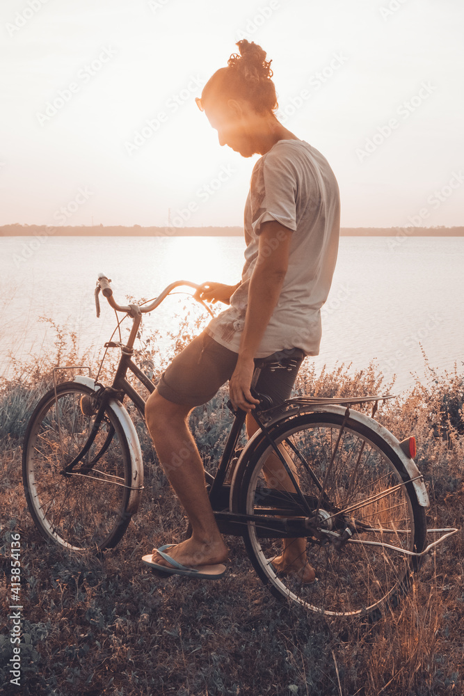 Man smiling while standing on his bicycle outdoor in summer Man smiling while standing on his bicycle outdoor in summer