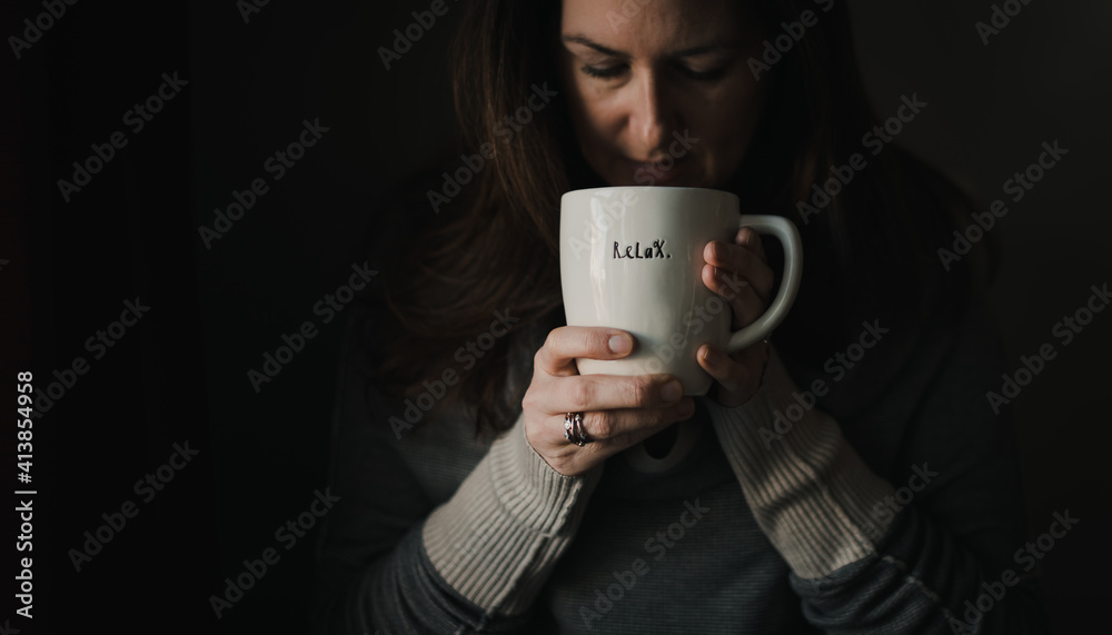 Woman drinking from large coffee mug with word relax written on it. Woman drinking from large coffee mug with word relax written on it.
