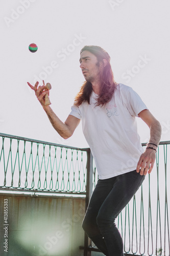 A man playing with a kendama in a small square