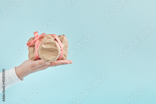 Female hand give a camera wrapped in craft paper. Mysterious surprise, gift