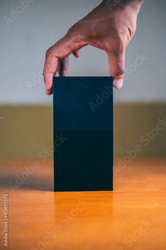 Arima, Trinidad and Tobago - June 6, 2019: A male hand holding a blank black box on top of a table. photo