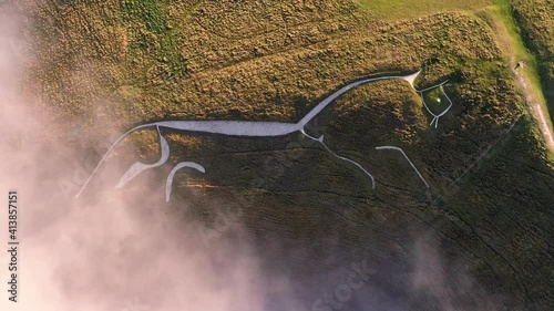 4k rising birds-eye footage of Uffington White Horse in Oxfordshire. The Uffington White Horse is a prehistoric hill figure, 110 m long, formed from deep trenches filled with crushed white chalk. photo