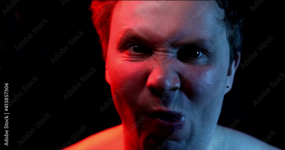 Close-up of the face of Caucasian man who is making faces at the camera, different grimaces with his facial expressions. Crazy man Head screaming. Negative emotion. Black background Close-up of the face of Caucasian man who is making faces at the camera, different grimaces with his facial expressions. Crazy man Head screaming. Negative emotion. Black background