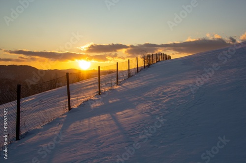 Sunset over fence in snowy mountains