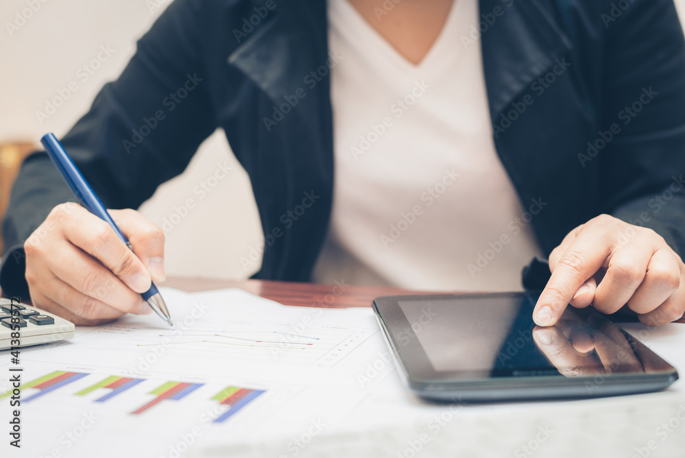 business woman hand hold pen and using calculator and pointing on tablet mobile technology for analysis and budget financial accounting with growth statistics chart and graph on paper work. business woman hand hold pen and using calculator and pointing on tablet mobile technology for analysis and budget financial accounting with growth statistics chart and graph on paper work.